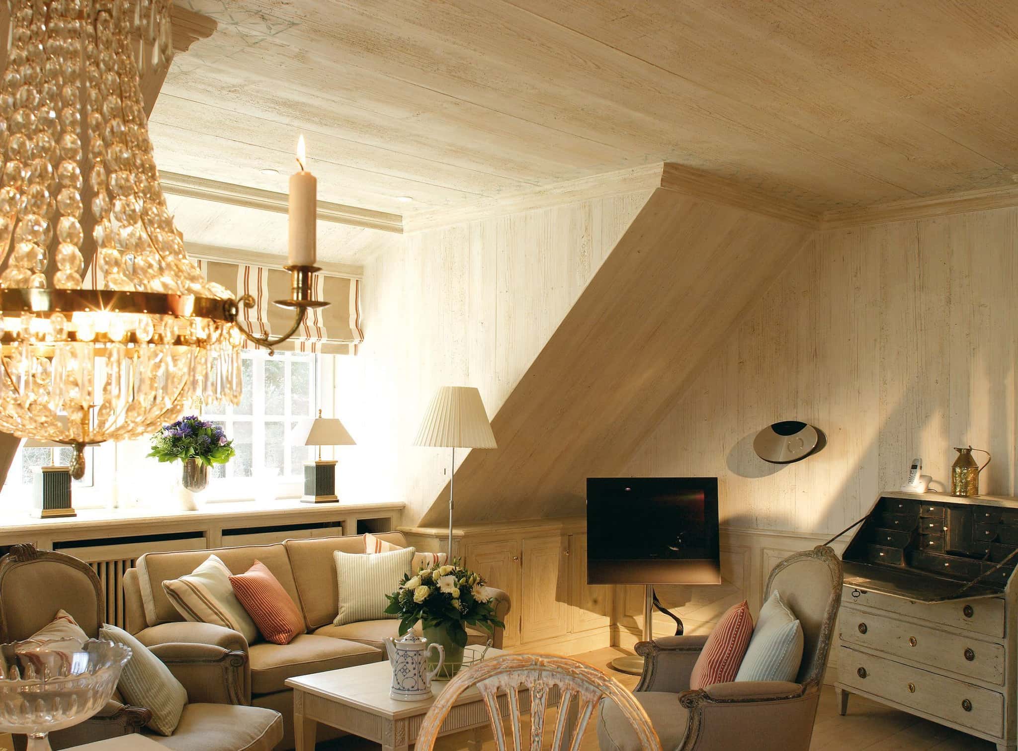 Wohnzimmer mit Sofa, Sesseln, Kronleuchter und Sekretär unter der Dachschräge, Ferienwohnung Tipkenhoog